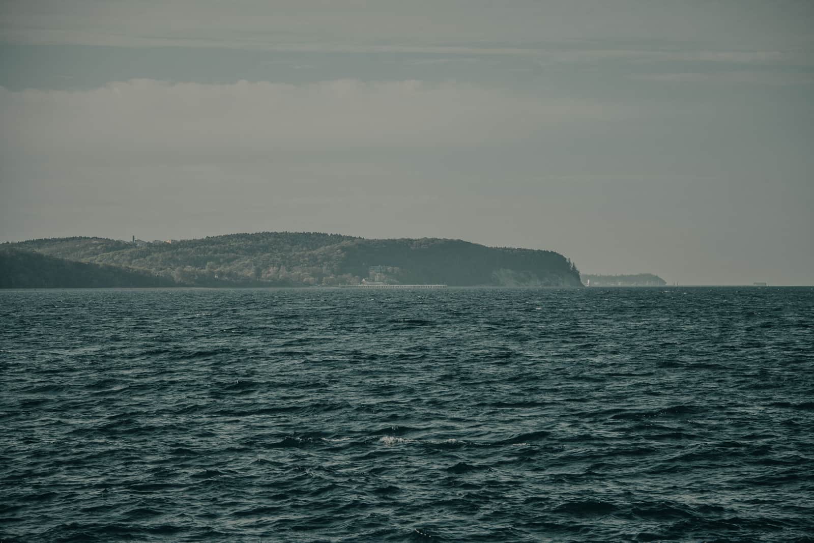 Open gray bay water under an overcast sky with a distant headland