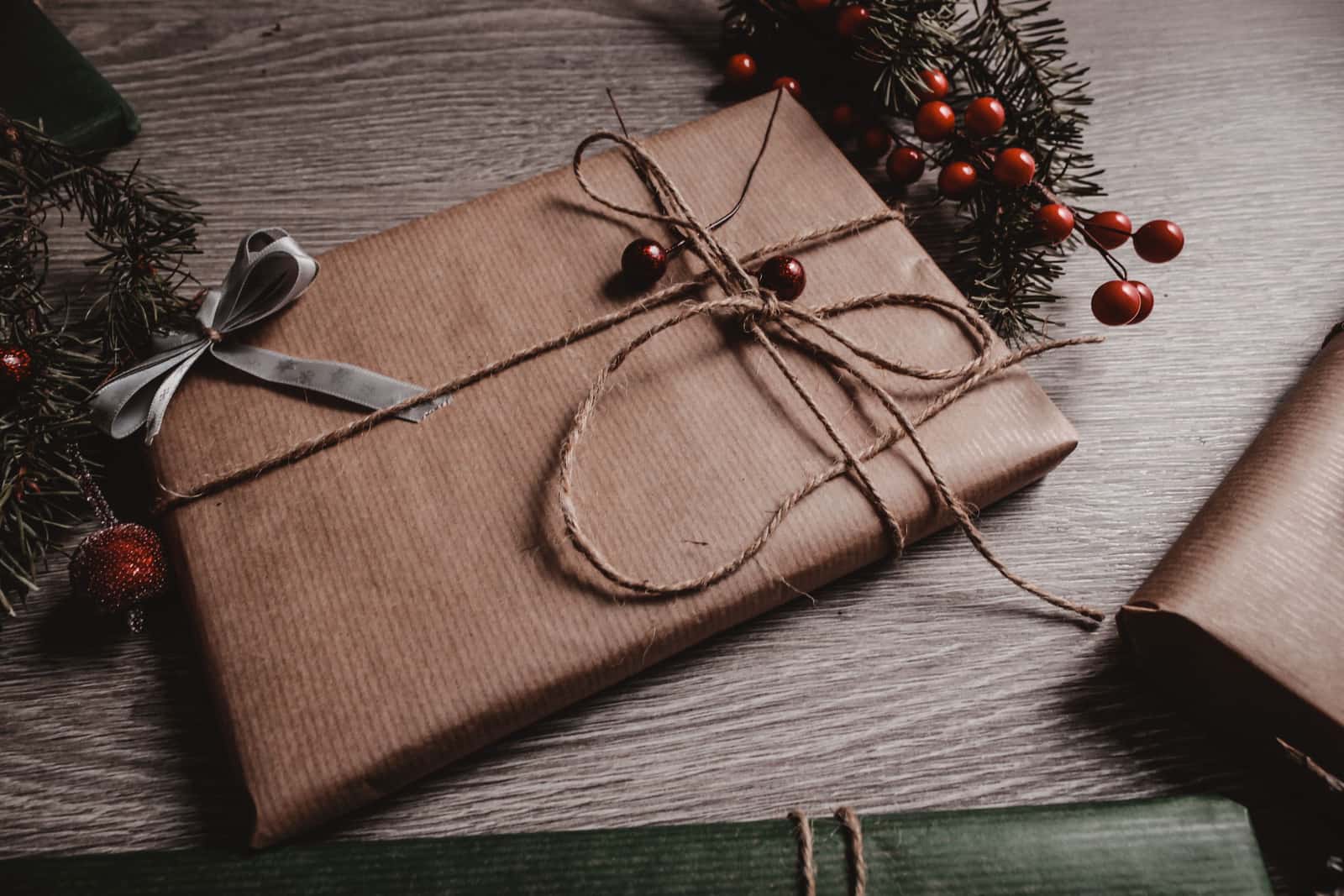 Gift wrapped in brown kraft paper and twine with pine sprigs and berries