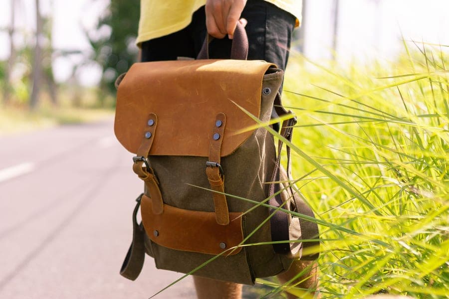 Olive canvas and leather backpack carried through tall green grass