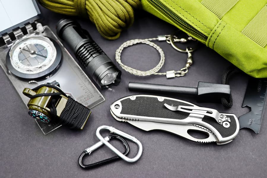 Whistle, olive paracord, carabiners and a compass laid out with small field gear
