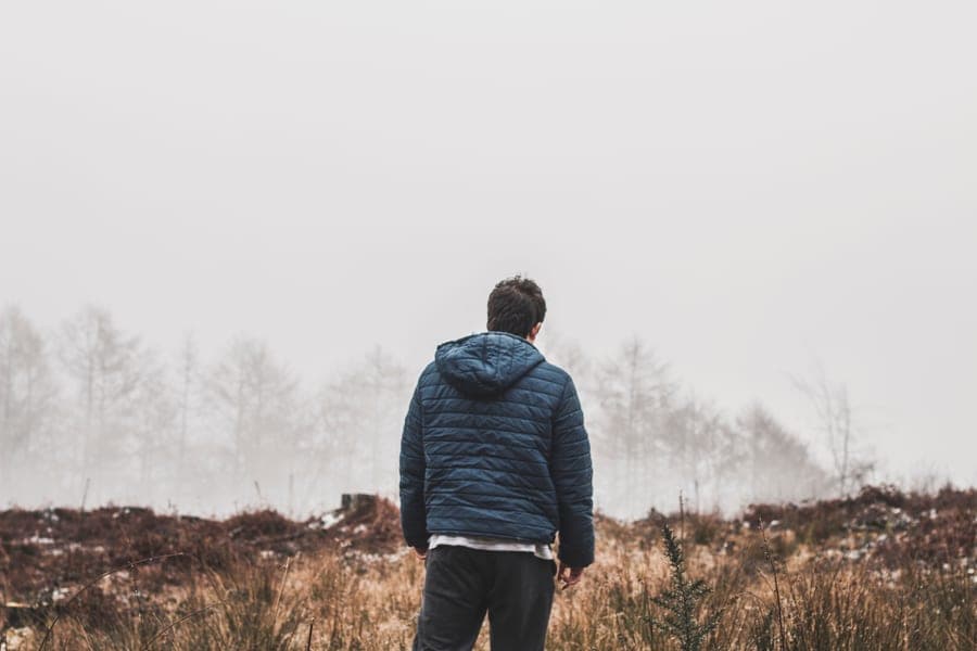 Person in a navy puffer jacket seen from behind in a foggy winter field