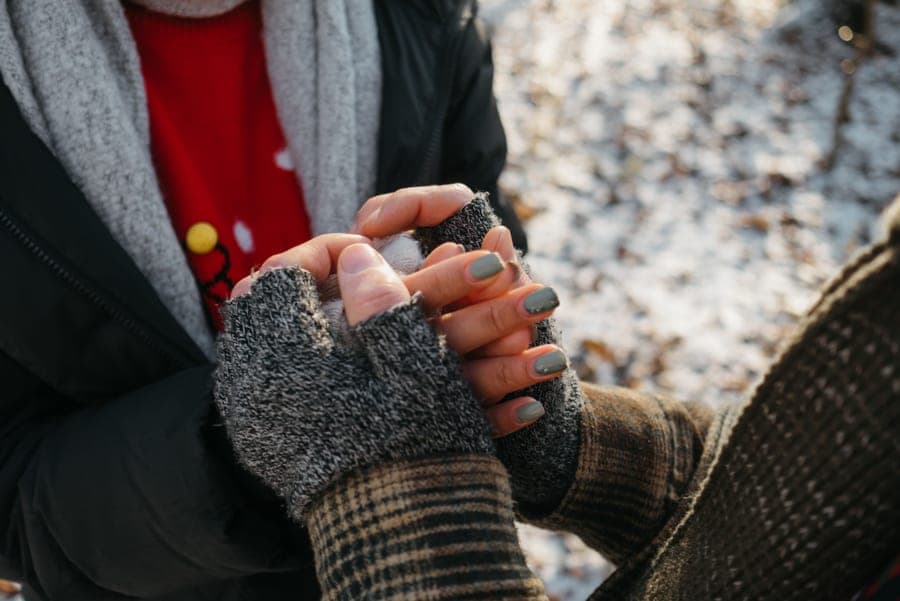Hands in fingerless wool gloves rubbing together for warmth outdoors